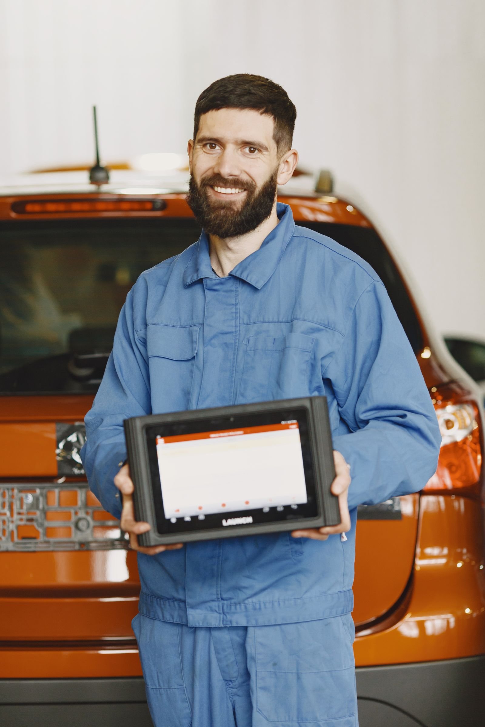 Mechanic holding an Autel diagnostic scan tool while working on a European car
