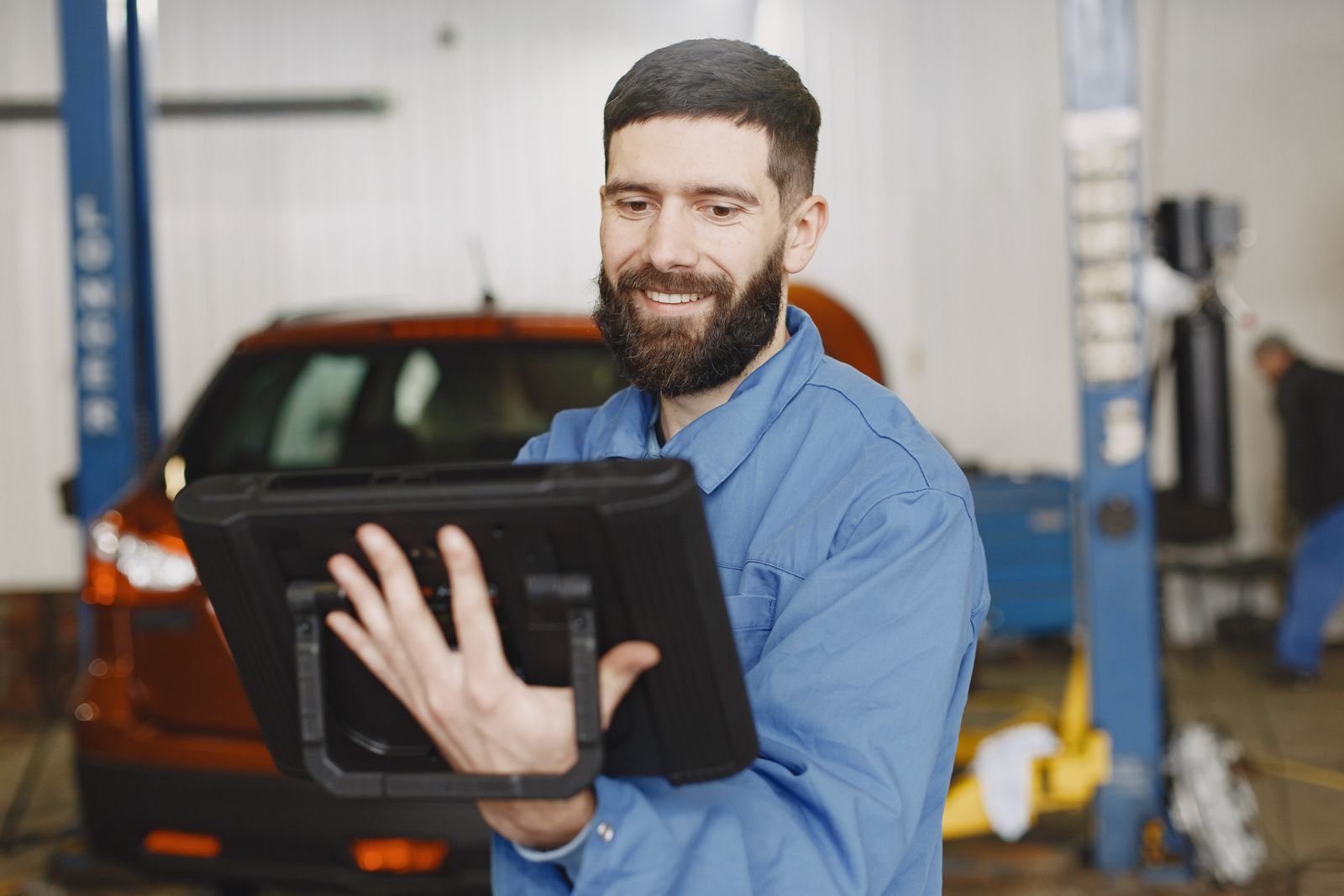 Technician holding an Autel diagnostic tablet during a software update and activation
