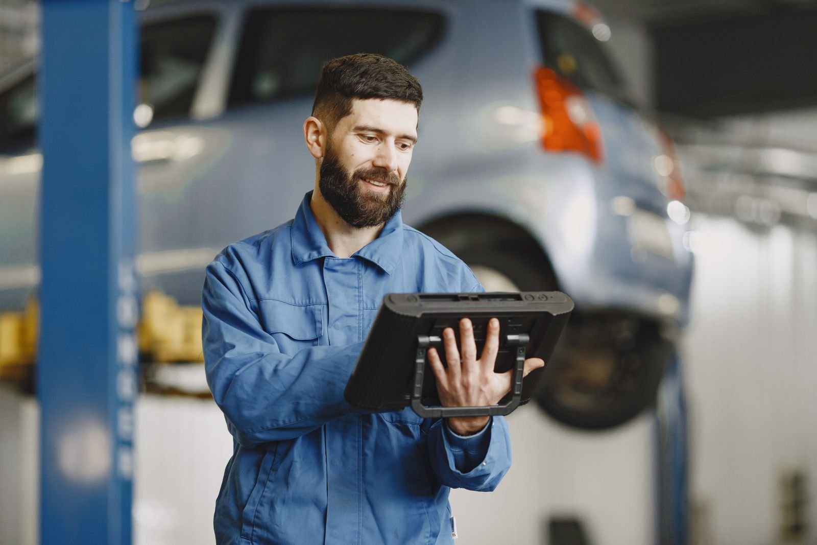 Technician reviewing multi-brand vehicle repair data on a tablet in an auto repair shop